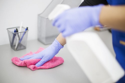 Office cleaner sanitising desks and shared surfaces in Putney